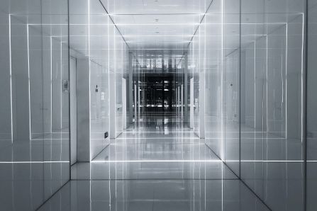 A long hallway, grey with beams of light in it. Going towards a dark ending.